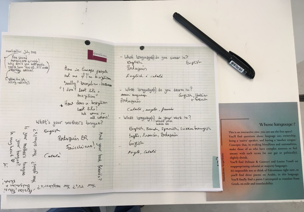 white desk, black pen, an open zine with questions on language and answered in different handwriting so evidently by different people